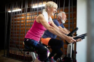 Happy mature people doing indoor biking in a fitness club